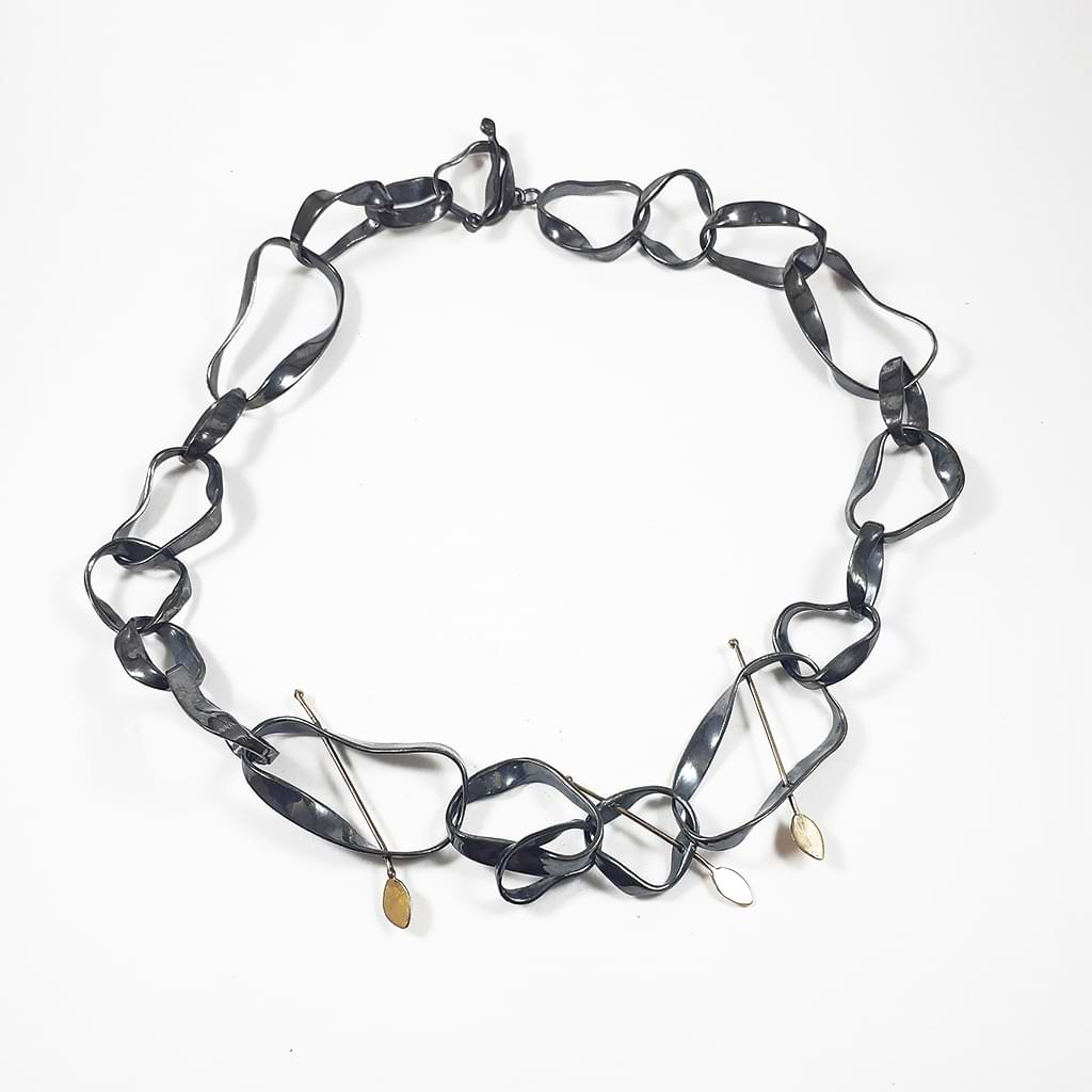 Niki Boli. Necklace with a special sculptural design made of silver with three golden arrows.
